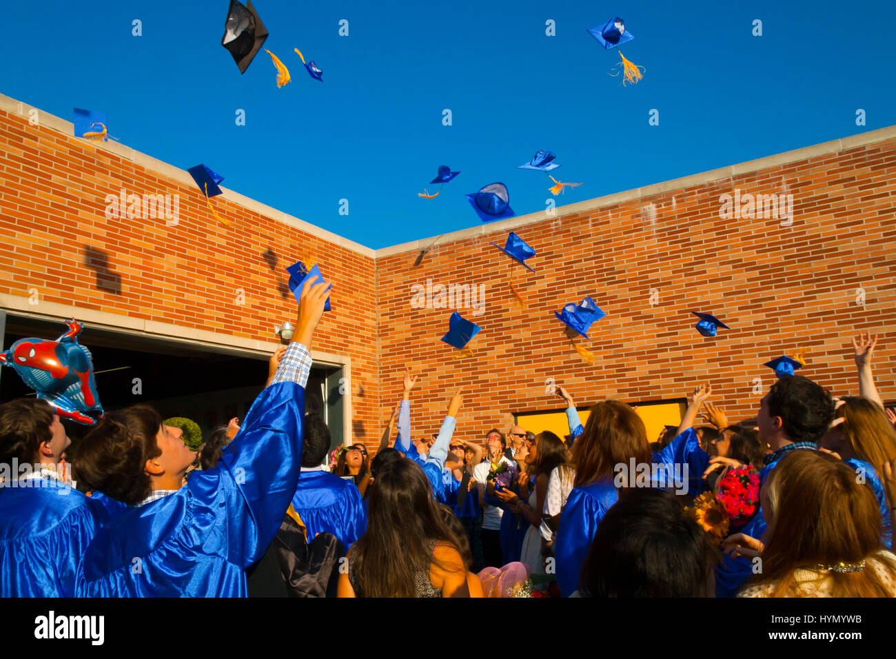 High School graduates in gowns throwing caps in the air Stock Photo