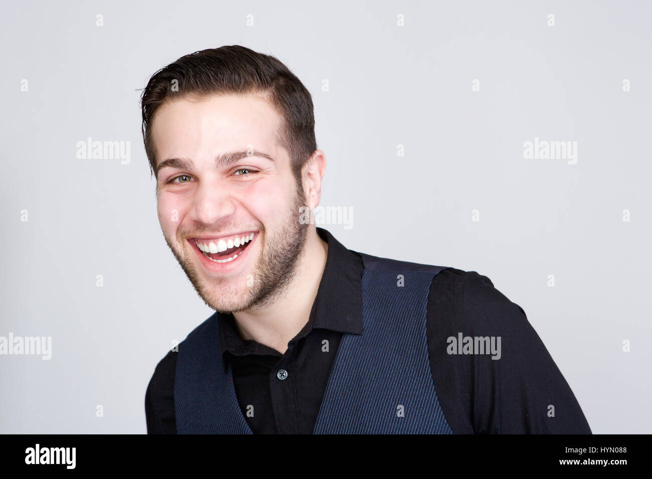 Close up portrait of a handsome young man smiling on isolated gray ...