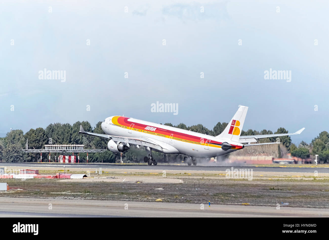 Plane Airbus A330, of spanish airline Iberia, is landing in Madrid - Barajas, Adolfo Suarez airport. Touching the runway. Blue sky with clouds. Stock Photo