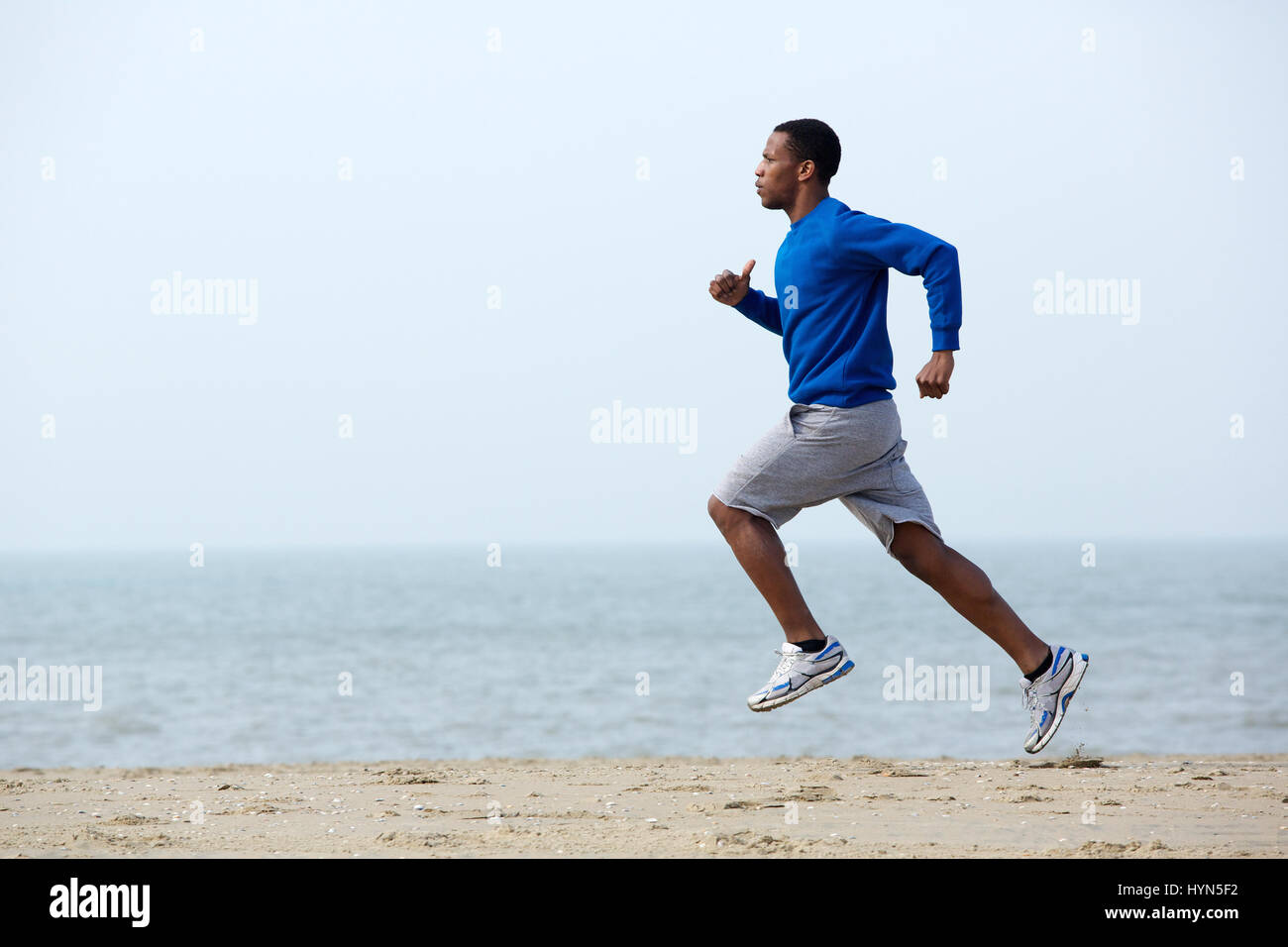 Healthy young athletic man running at the beach Stock Photo