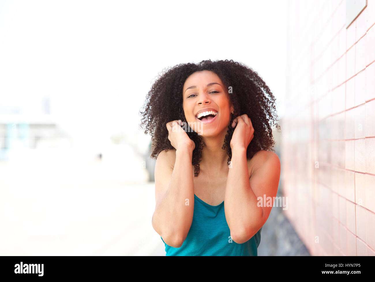 Close up portrait of a cheerful young black woman laughing outdoors ...