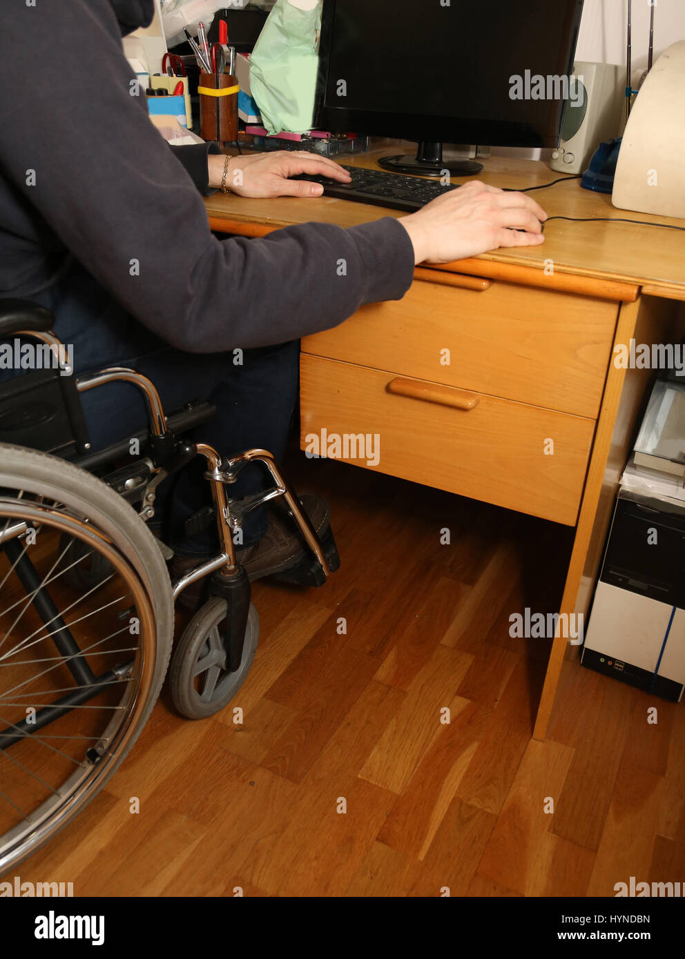 young disabled man in a wheelchair using the computer with mouse on the