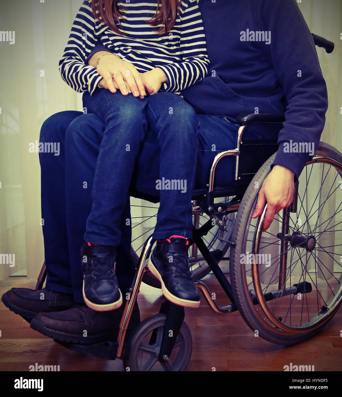 young disabled parent in a wheelchair with her baby in his legs and