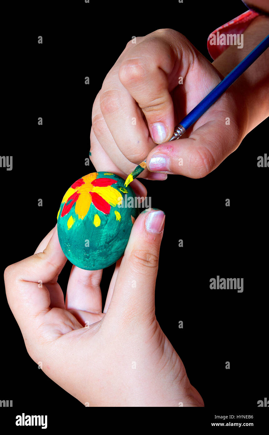 Child decorates Easter egg with brush and paint. Stock Photo