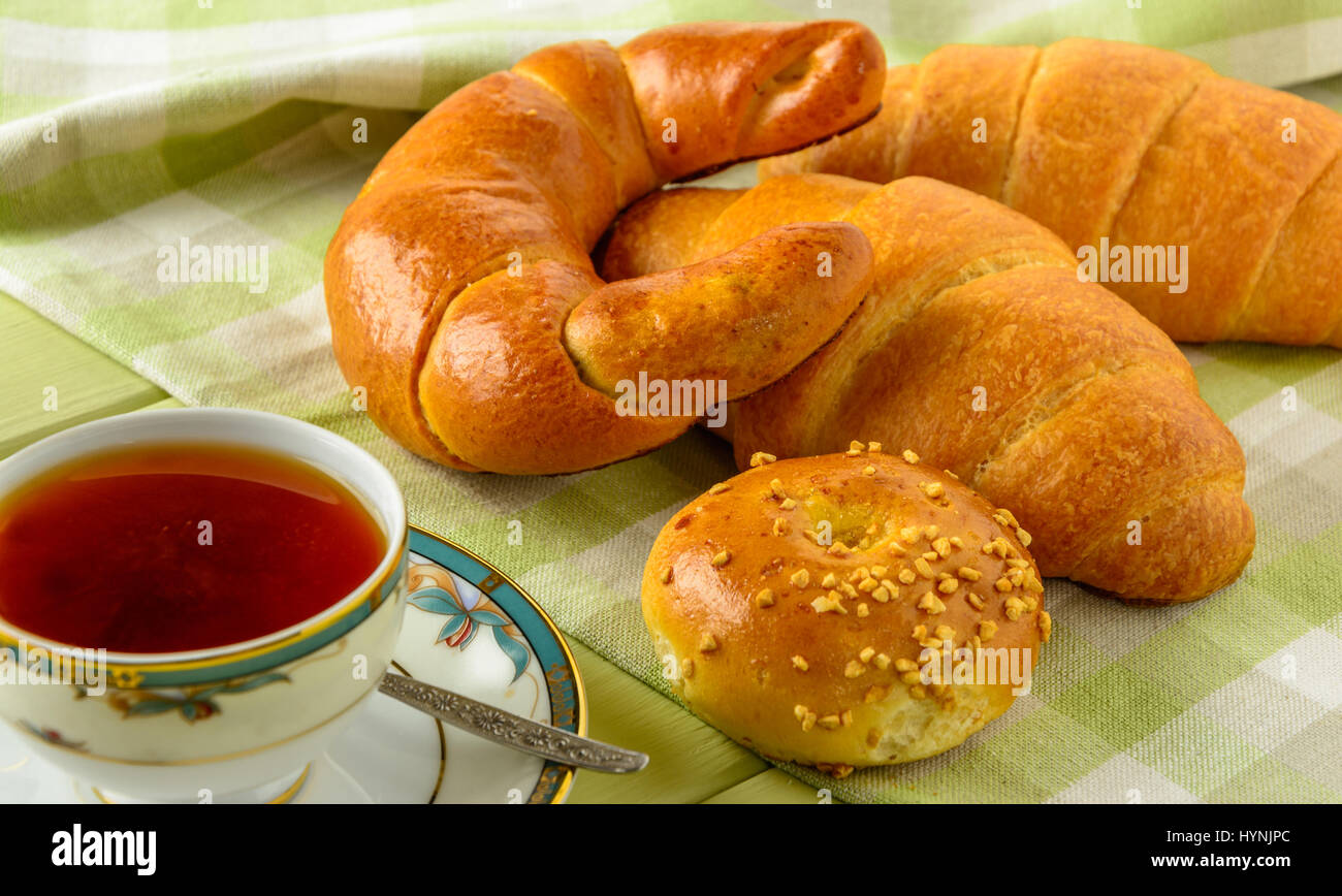 Healthy breakfast ingredients. Homemade fresh fragrant buns and cup of tea . The food is rich in useful carbohydrates, vitamins and nutrients that are Stock Photo