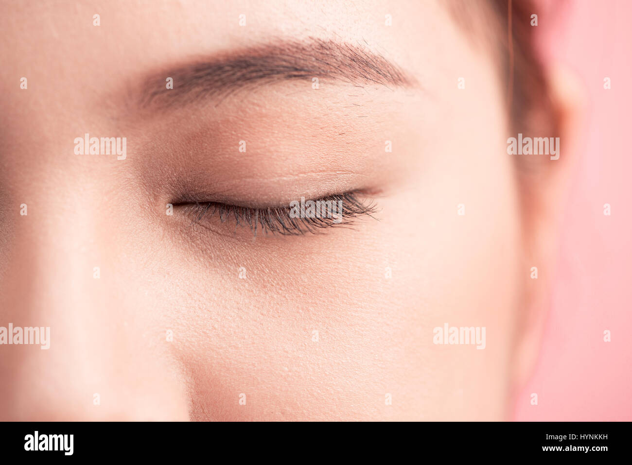 Beautiful asian woman eye with long eyelashes isolated on pink background. Stock Photo