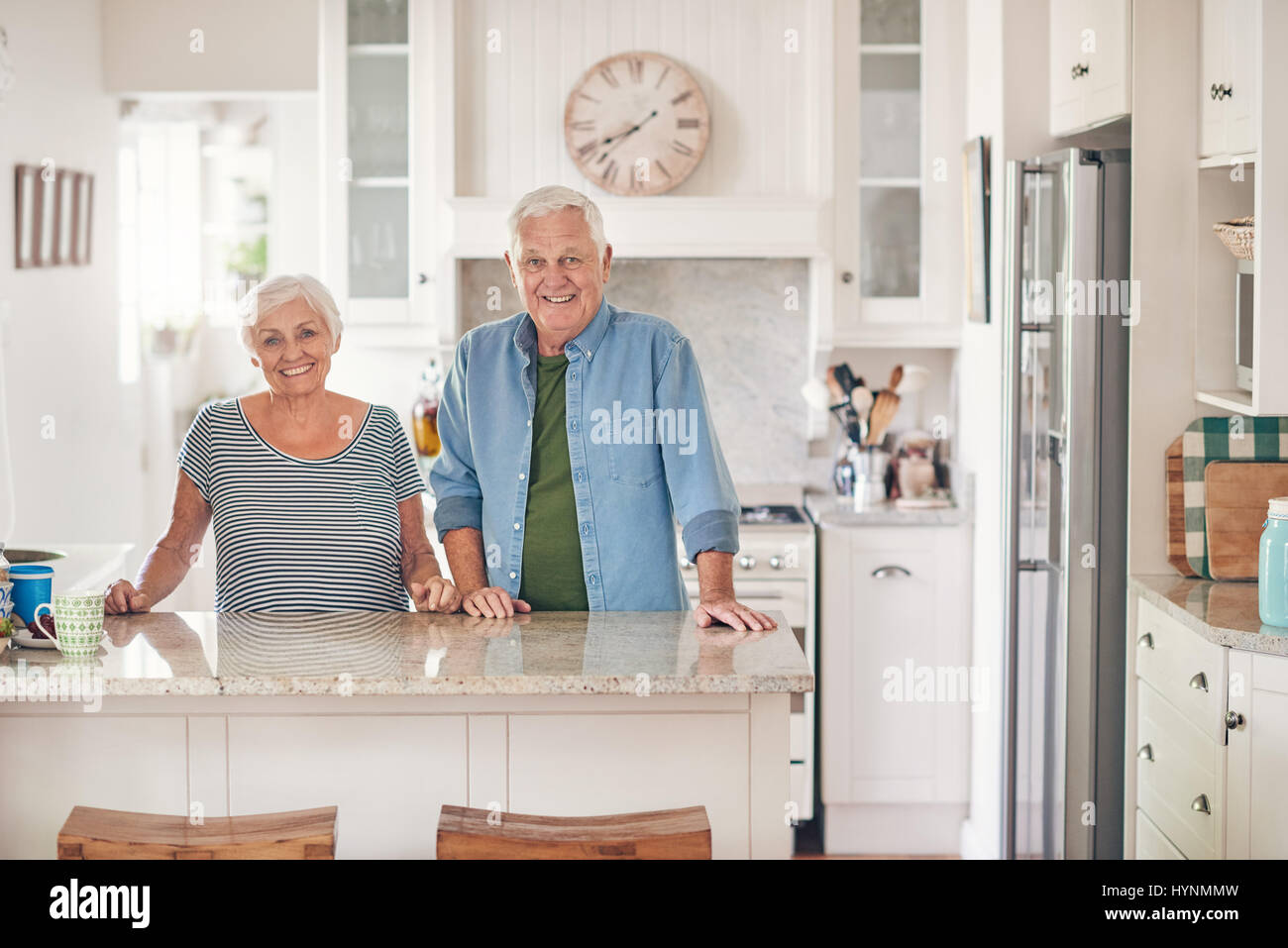 Smiling senior couple standing at their kitchen counter at home Stock Photo