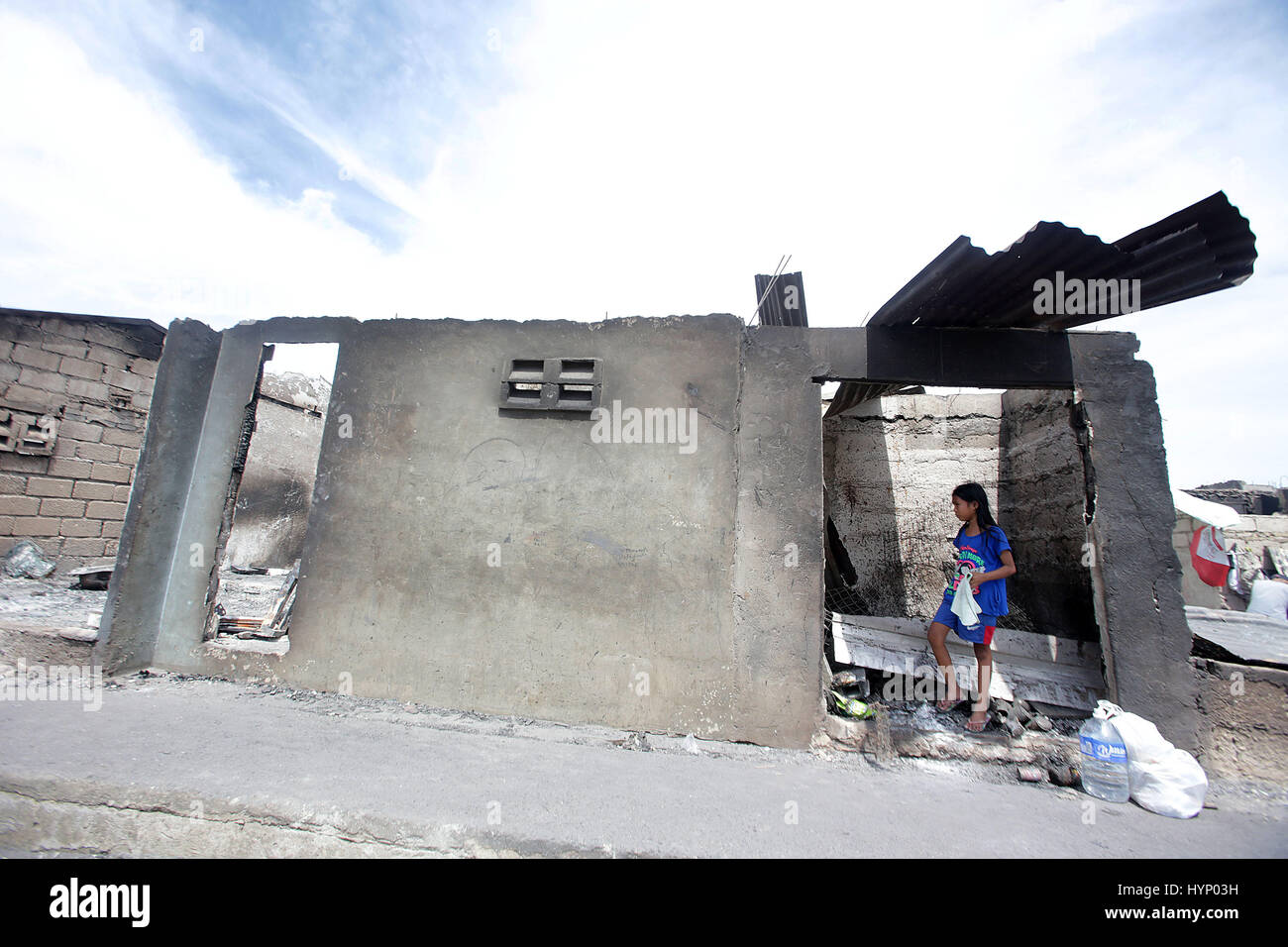 (170406) -- CAVITE, April 6, 2017 (Xinhua) -- A girl stands in her burnt house after a fire at a coastal slum area in Cavite Province, the Philippines, April 6, 2017. More than 600 shanties were razed in the fire, leaving 1,000 families homeless. (Xinhua/Rouelle Umali) (djj) Stock Photo