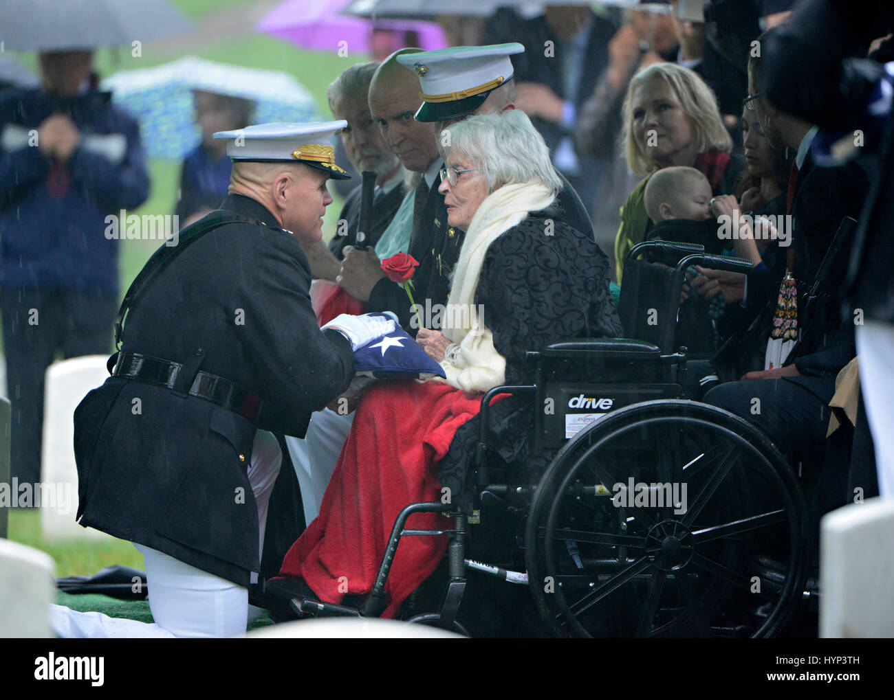 Arlington, Virginia, USA. 6th Apr, 2017. Commandant of the Marine Corps Gen. Robert Neller, left, presents the American flag to Annie Glenn, widow of John Glenn, during the graveside service in Section 35 of Arlington National Cemetery April 6, 2017 in Arlington, Virginia. Glenn, the first American astronaut to orbit the Earth and later a United States senator, died at the age of 95 on December 8, 2016. Credit: Planetpix/Alamy Live News Stock Photo