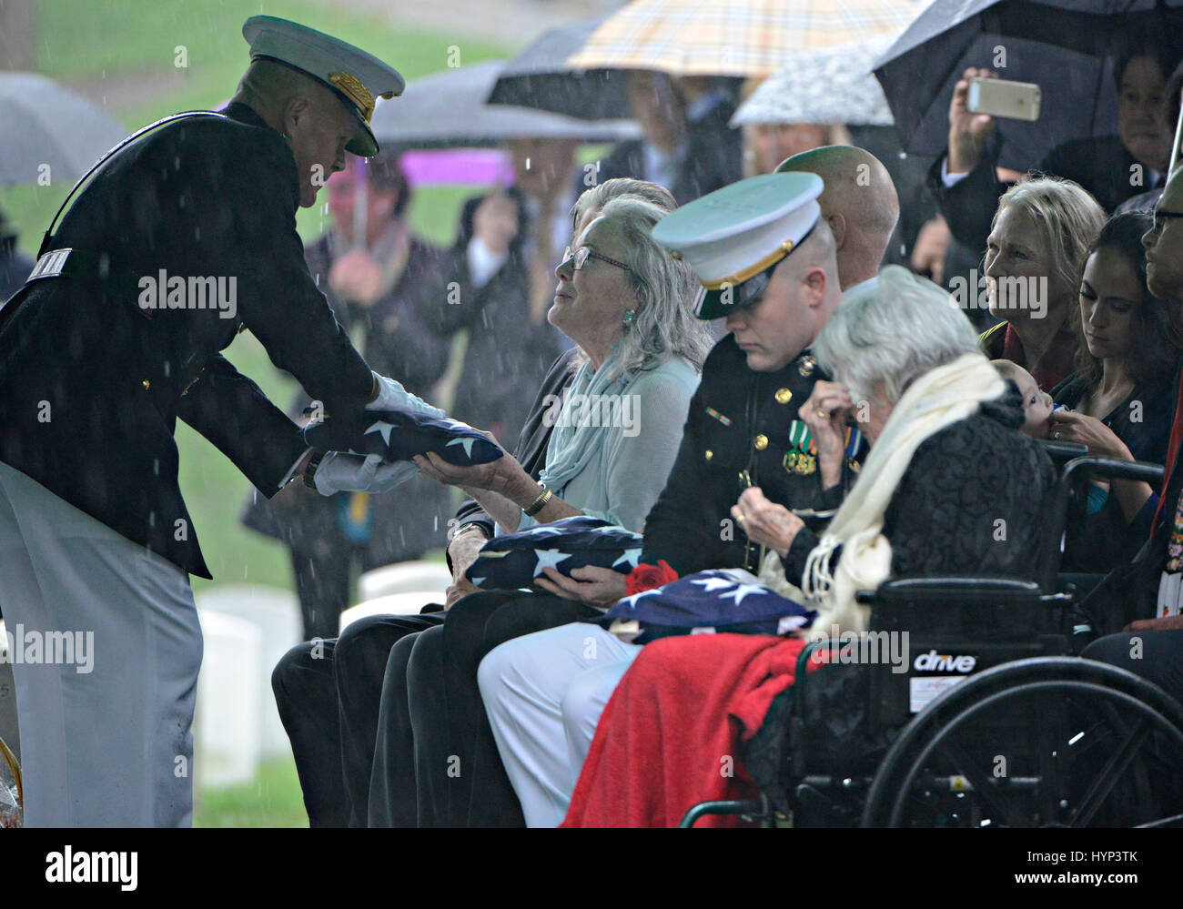Arlington, Virginia, USA. 6th Apr, 2017. Commandant of the Marine Corps Gen. Robert Neller, left, presents the American flag to Carolyn Glenn, daughter of John Glenn as window Annie Glenn is comforted during the graveside service in Section 35 of Arlington National Cemetery April 6, 2017 in Arlington, Virginia. Glenn, the first American astronaut to orbit the Earth and later a United States senator, died at the age of 95 on December 8, 2016. Credit: Planetpix/Alamy Live News Stock Photo
