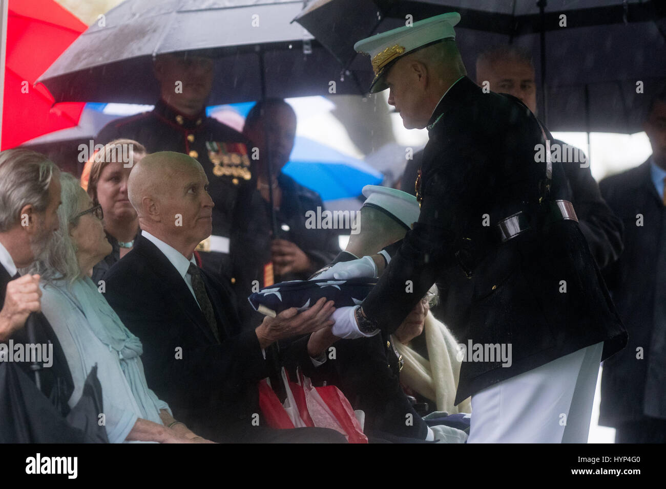 Arlington, United States Of America. 06th Apr, 2017. Commandant of the Marine Corps Gen. Robert Neller, right, presents the American flag to David Glenn, son of John Glenn, during the graveside service in Section 35 of Arlington National Cemetery April 6, 2017 in Arlington, Virginia. Glenn, the first American astronaut to orbit the Earth and later a United States senator, died at the age of 95 on December 8, 2016. Credit: Planetpix/Alamy Live News Stock Photo