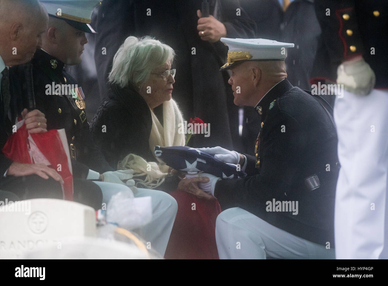 Arlington, United States Of America. 06th Apr, 2017. Commandant of the Marine Corps Gen. Robert Neller, right, presents the flag to Anne Glenn, widow of John Glenn, during the graveside service in Section 35 of Arlington National Cemetery April 6, 2017 in Arlington, Virginia. Glenn, the first American astronaut to orbit the Earth and later a United States senator, died at the age of 95 on December 8, 2016. Credit: Planetpix/Alamy Live News Stock Photo