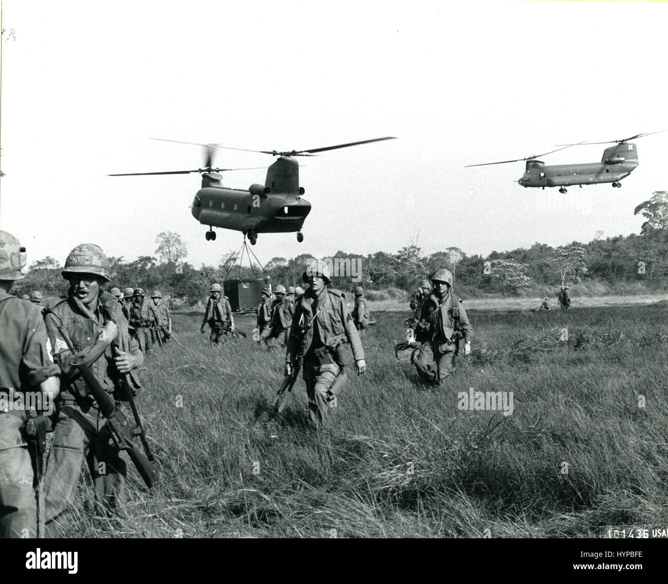 US Army troops on the move in South Vietnam during OPERATION JUNCTION CITY. Hovering in the background are Army CH-47 Chinook helicopters, 1967. Stock Photo
