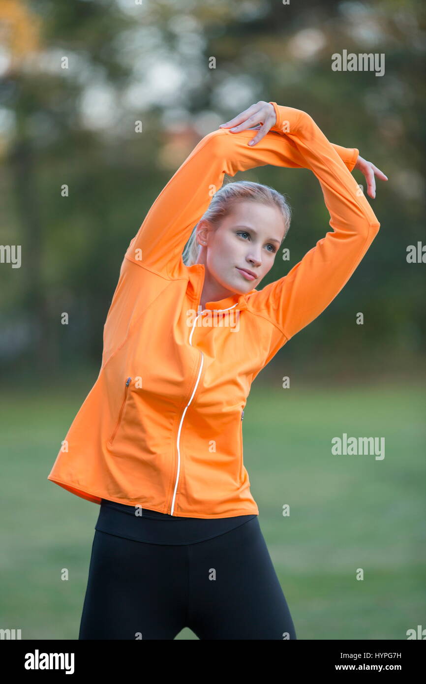 Pretty blonde woman stretching in park Stock Photo - Alamy