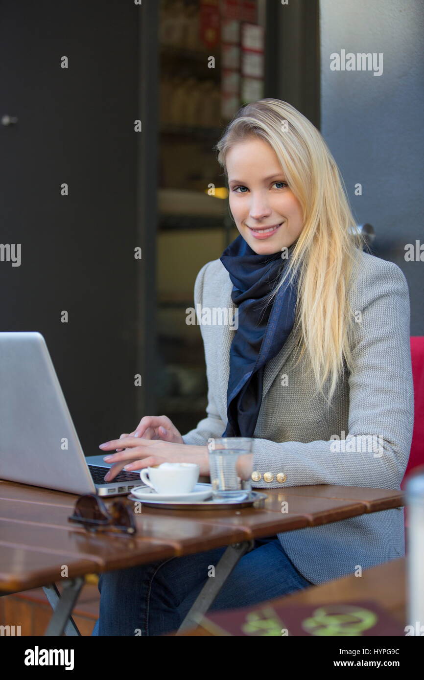 Pretty blonde woman with laptop in a Cafe smiling at camera Stock Photo ...