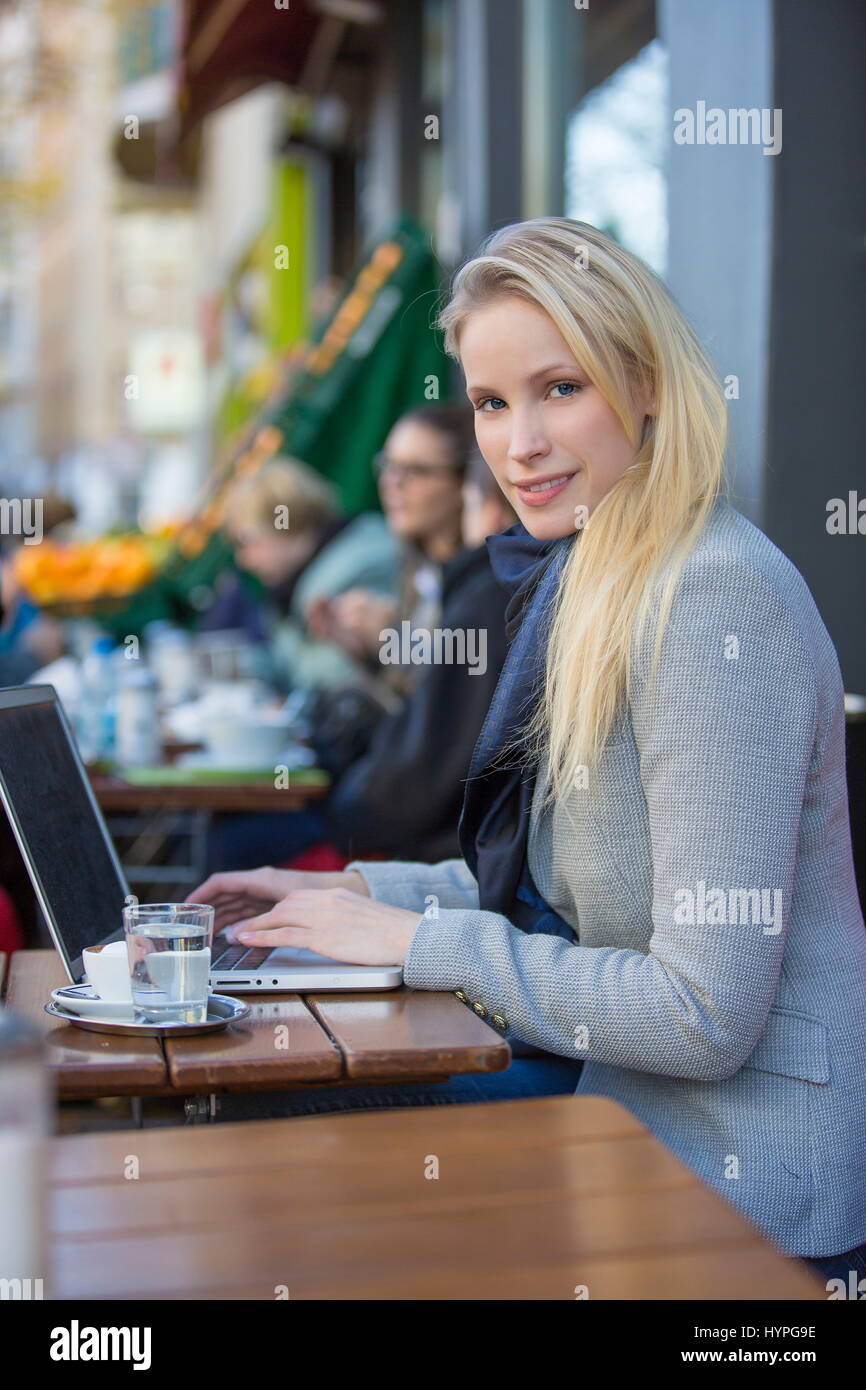 Pretty blonde woman with laptop in a Cafe smiling at camera Stock Photo ...
