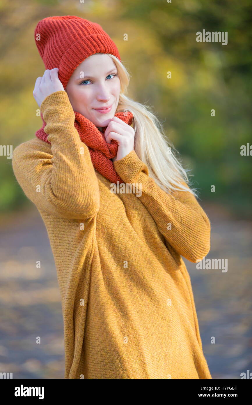 Portrait of a pretty blonde woman in park in autumn smiling at camera ...
