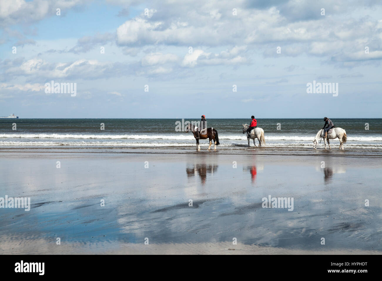 Three women on horseback on Saltburn beach on north east coast of England, UK Stock Photo