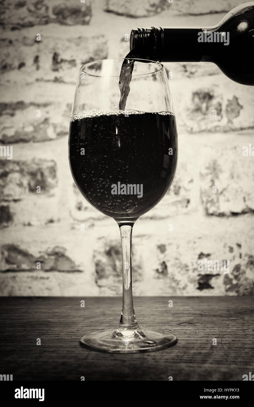 Glass of full bodied red wine being poured from bottle Stock Photo