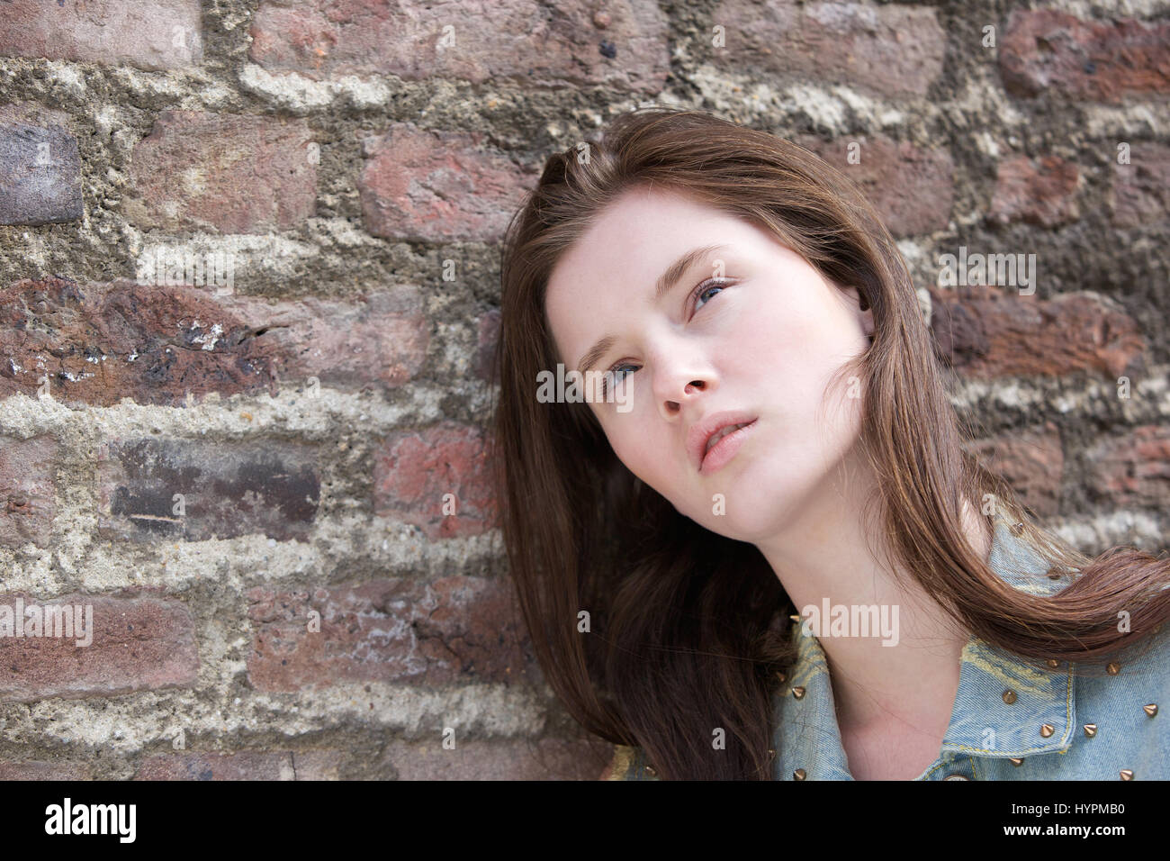 Close up portrait of a female fashion model posing against brick wall outdoors Stock Photo