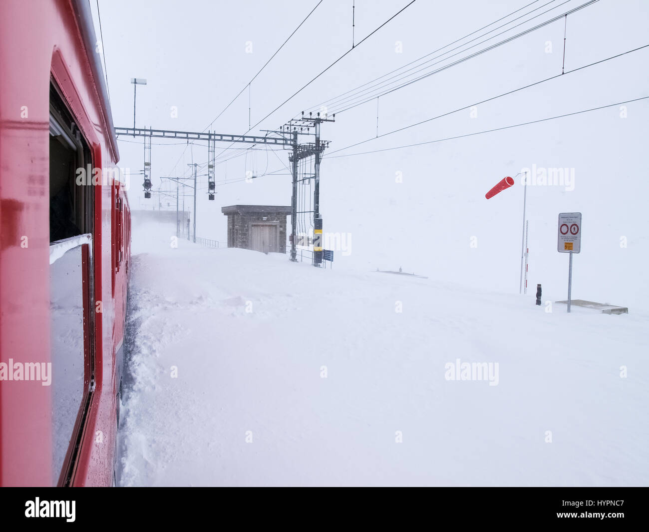 Bernina, Switzerland - April 27, 2016: trains of the Rhaetian Railway in transit along the line Tirano - St.Moritz during a snowy day. Stock Photo