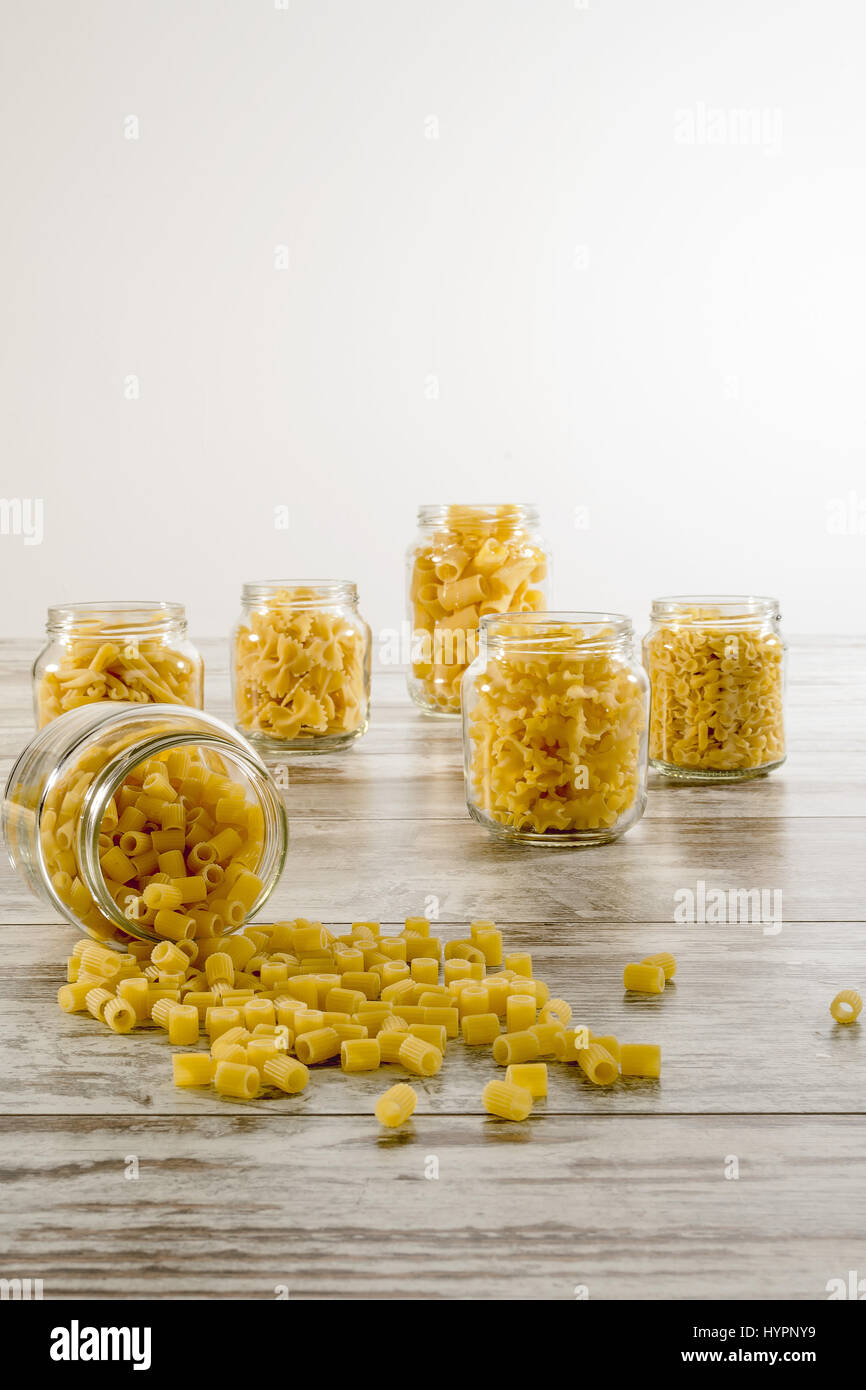 short pasta in glass jar upside down in front fingering Stock Photo