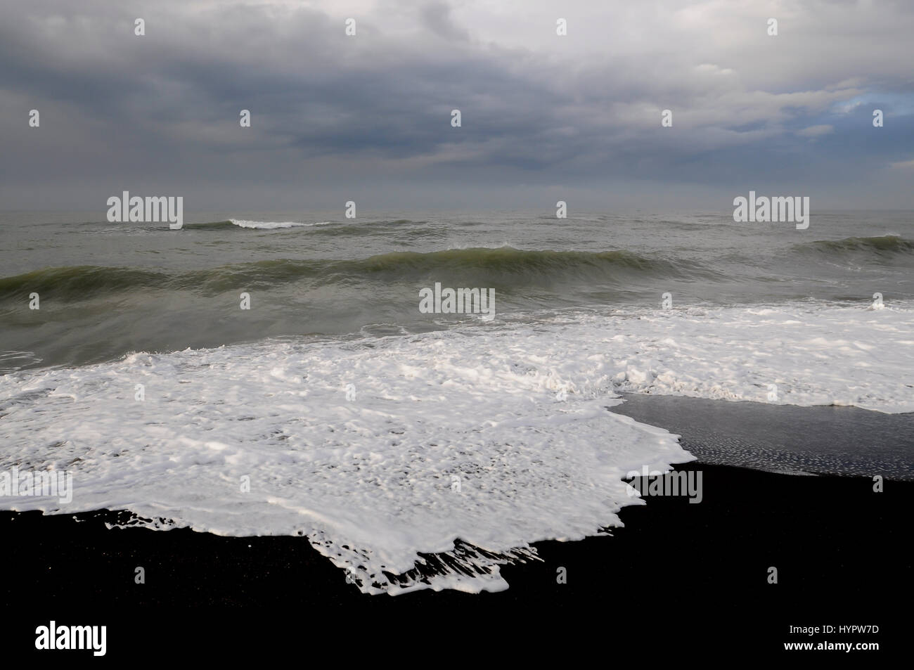 White foam covers the surface of beach with black volcanic sand Stock ...