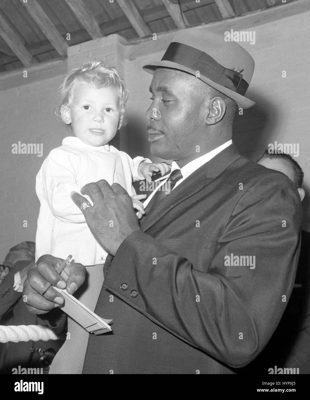 Sarah Walker, aged 21 months, meets American boxer Sonny Liston. Liston, paying a visit to the Pitsea, Essex, farm where British boxer Billy Walker has his training camp, had just watched the Briton training. Stock Photo