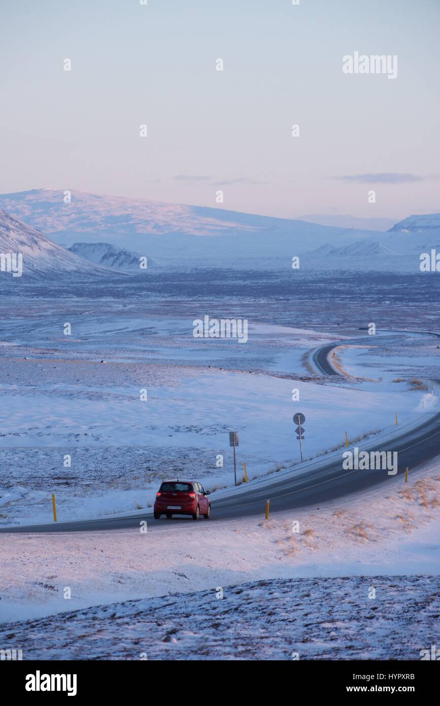 Driving through Iceland's volcanic landscape in winter in a red car Stock Photo