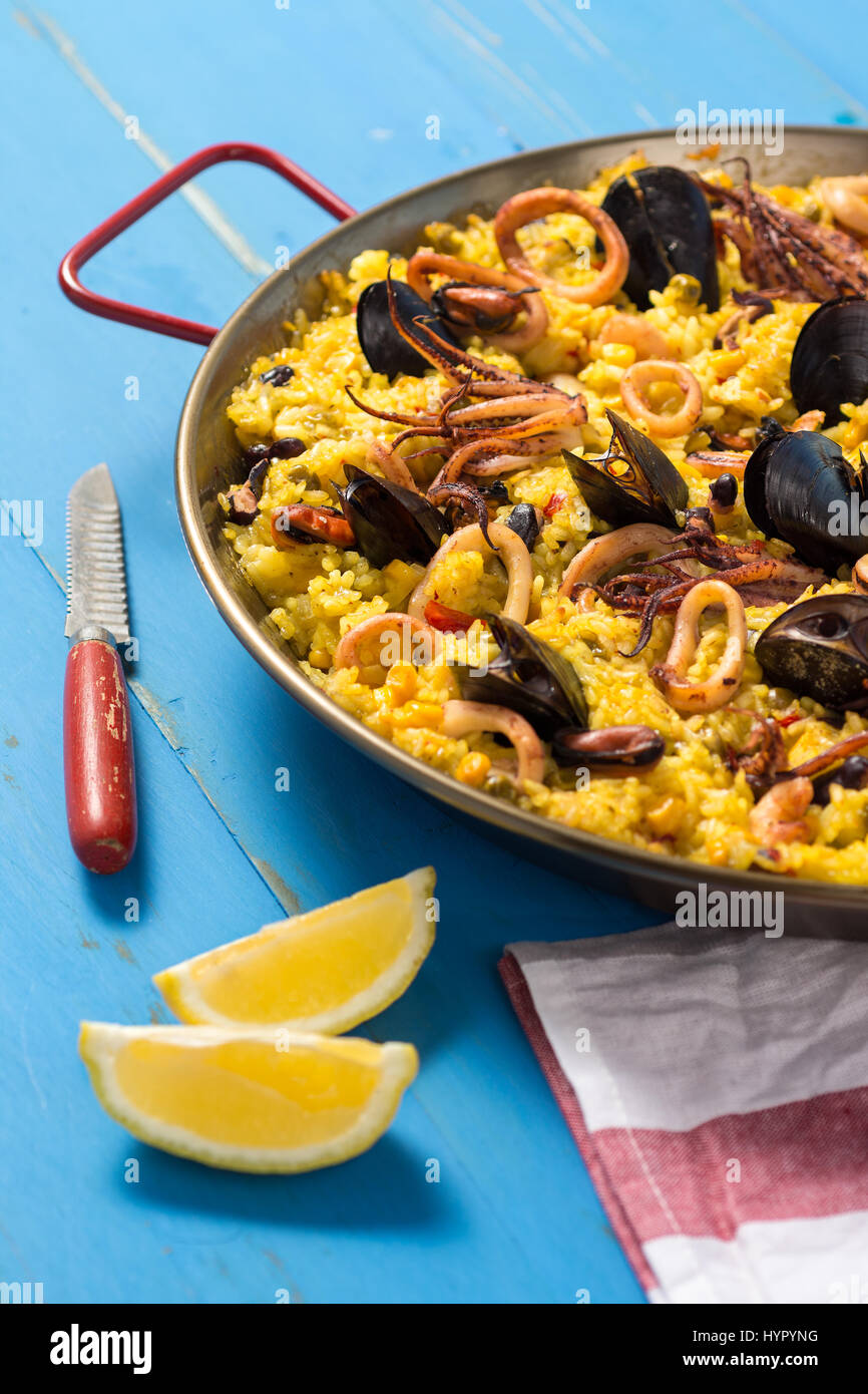 Spanish Seafood Paella in Traditional Pan on Rustic Wooden Table Stock Photo