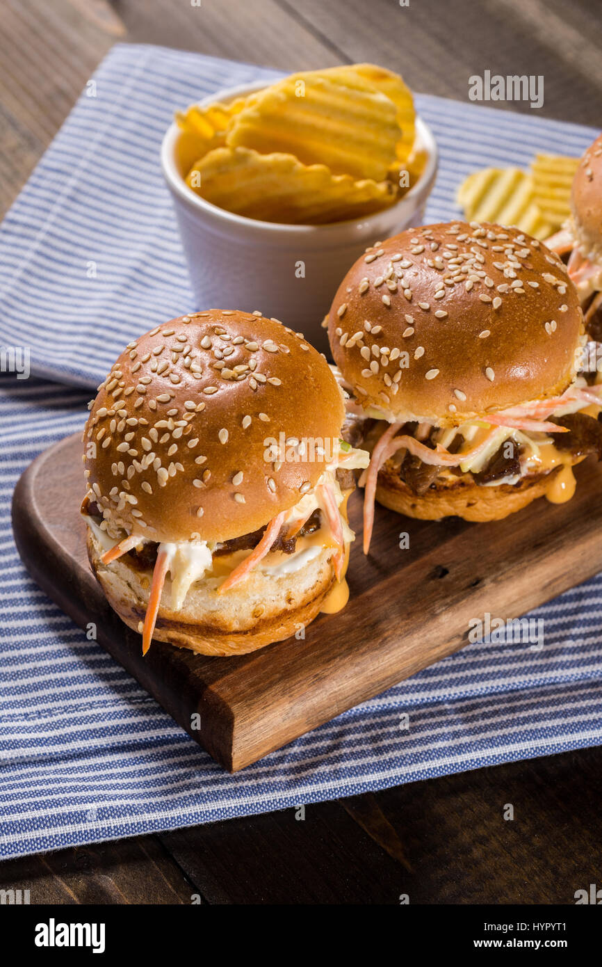 Homemade Mini Beef Burgers with Coleslaw Salad on Little Wooden Cutting Board. Barbecue Meat Sandwiches on Rustic Table. Stock Photo