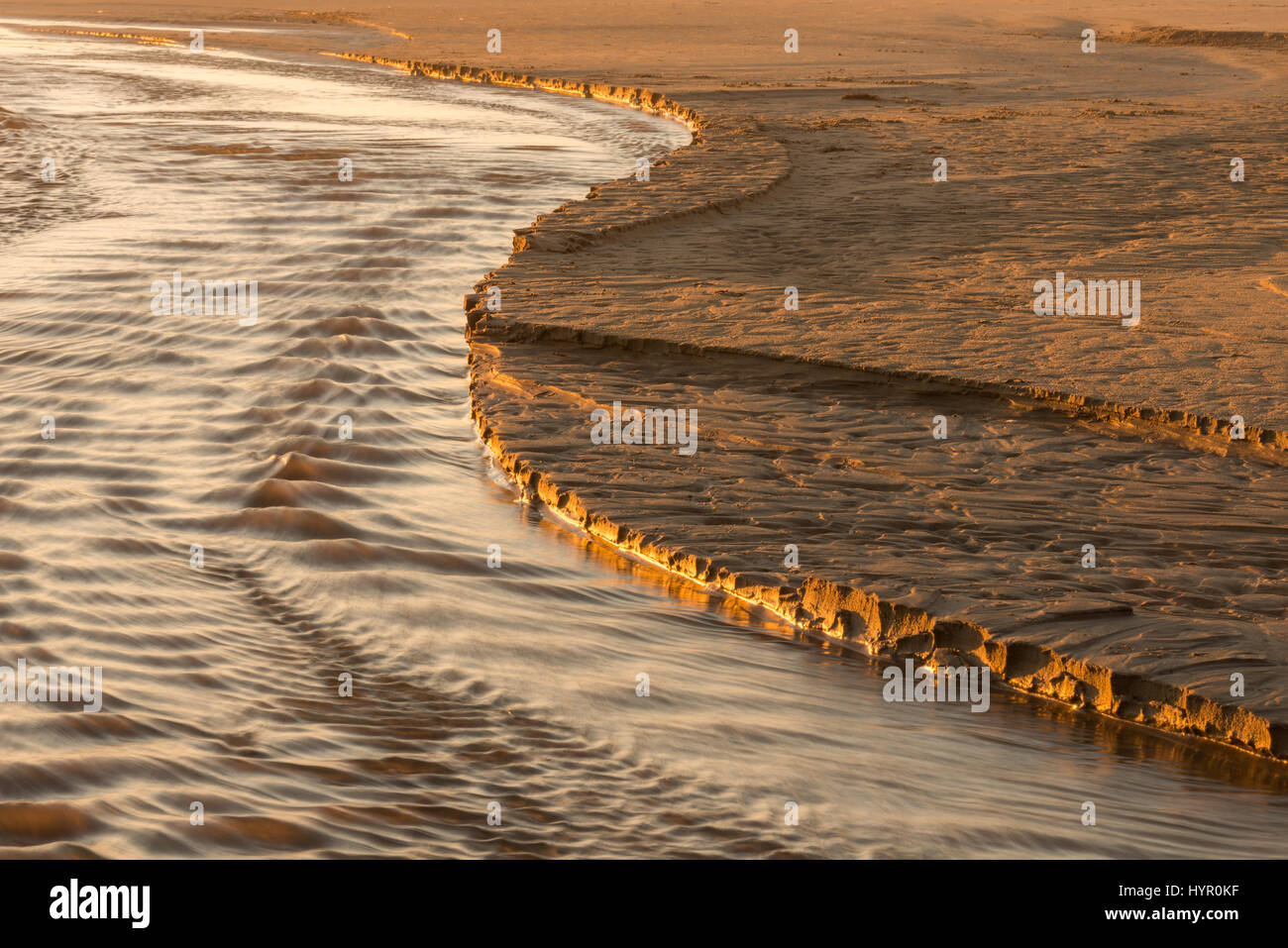 A natural S Curve in the sand on the edge edge of the water created by the outgoing tide along the Oregon Coast adjacent to the pacific Ocean Stock Photo