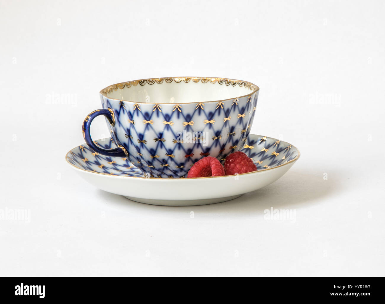 Ceramic set of a tea cup and a saucer with raspberries. Stock Photo