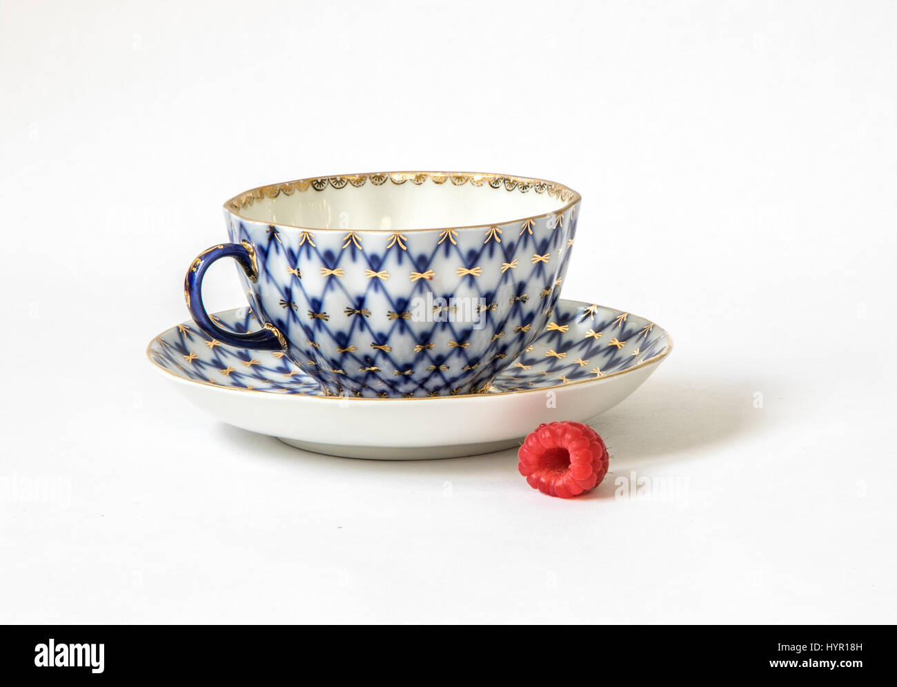 Ceramic set of a tea cup and a saucer with a raspberry. Stock Photo