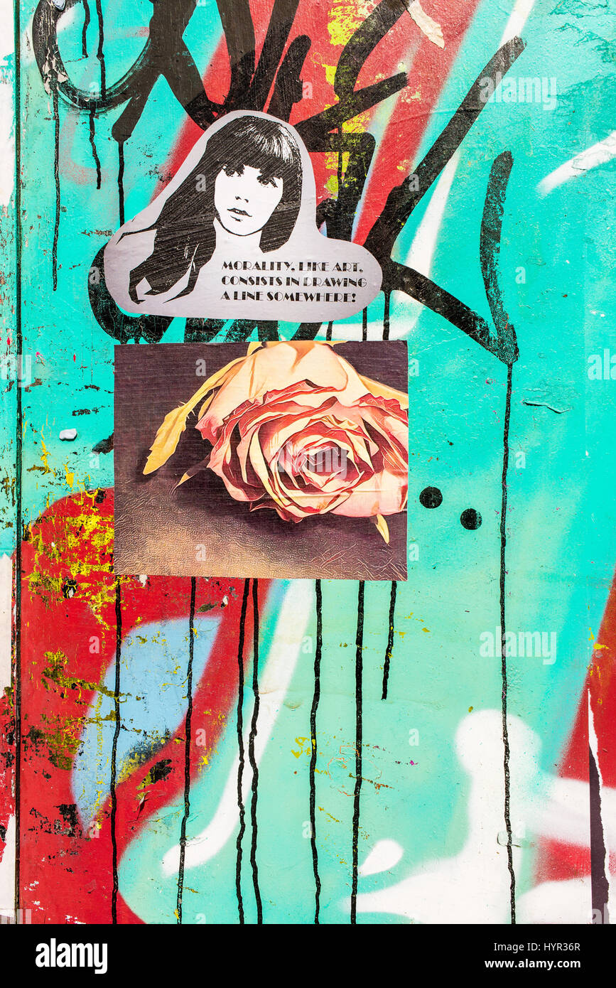 Sticker on a coluored wall with woman face and quote 'Morality, like art, consists in drawing a line somewhere!'. Poster with a rose attached below. Stock Photo