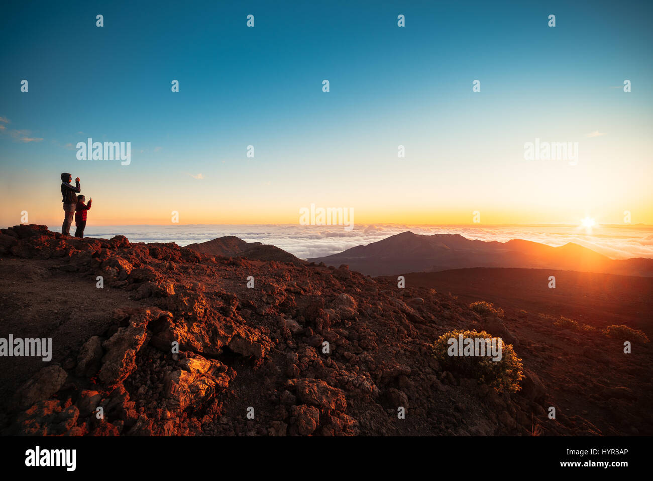 Tourists taking mobile photographs of the sunrise at the top of Haleakala mountain in Maui Stock Photo