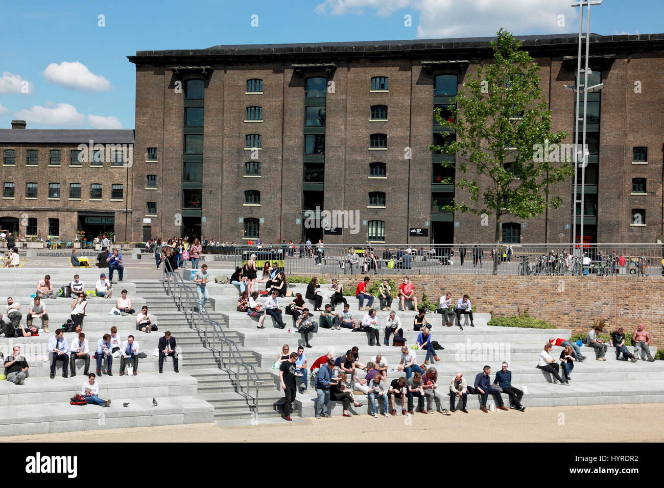 Students and office workers enjoying the sun in Granary Square by Regent’s Canal, King’s Cross, London Stock Photo