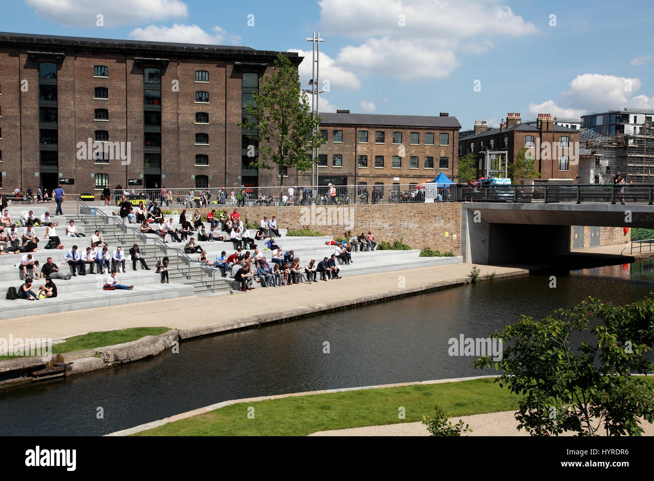 Students from Central St. Martins art school, UAL, enjoying the sun in Granary Square by Regent’s Canal, King’s Cross, London Stock Photo