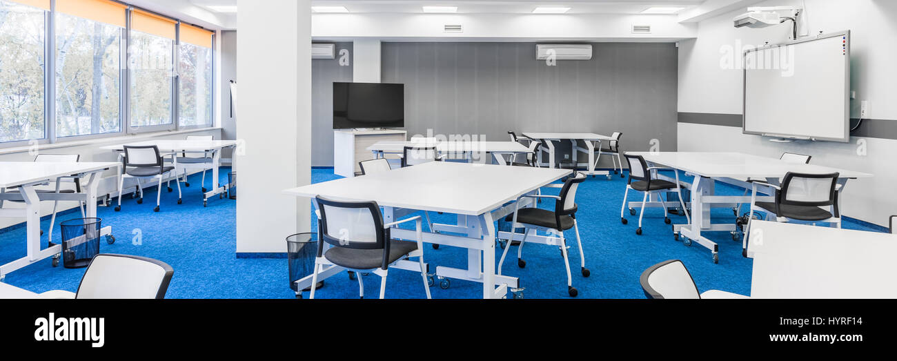 Panorama of modern college group study room with white desks, chairs