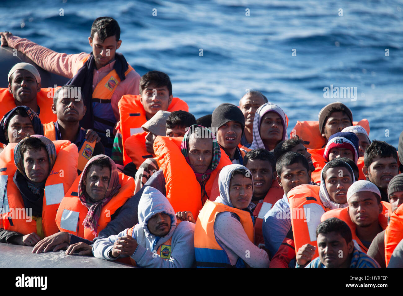 A non seaworthy rubberboat with around 150 people on board offshore Lybia trying to cross the mediterrean sea to europe. Because of the condition, whi Stock Photo