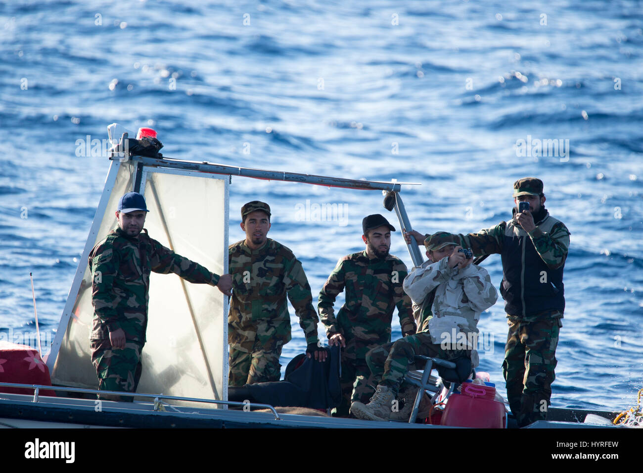 A small boat with 4 people, calling themself Libyan Coastguard was following a rubberboat with migrants and watching and documenting the SAR operation Stock Photo