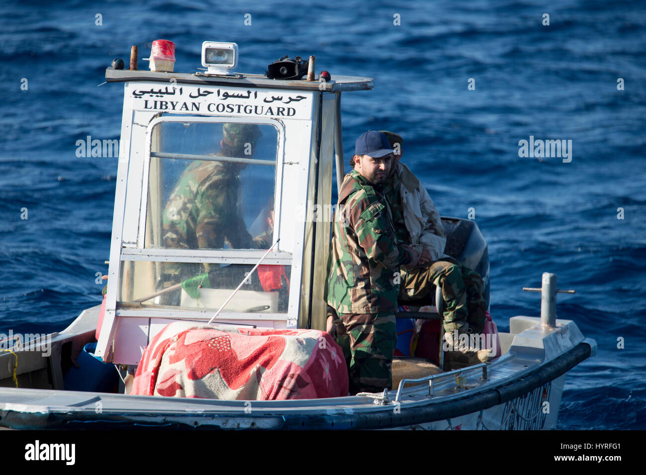 A small boat with 4 people, calling themself Libyan Coastguard was following a rubberboat with migrants and watching and documenting the SAR operation Stock Photo