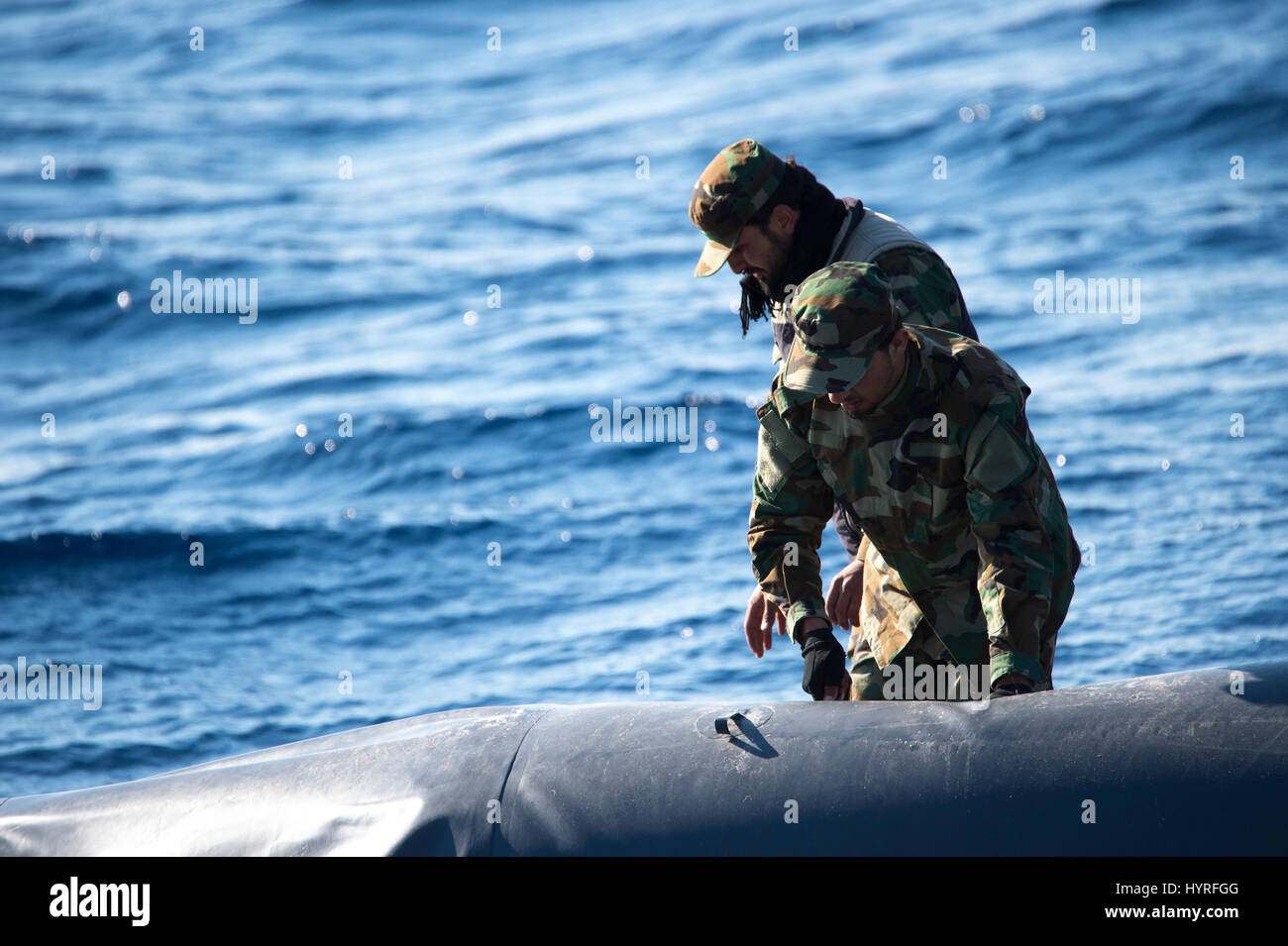 A small boat with 4 people, calling themself Libyan Coastguard was following a rubberboat with migrants and watching and documenting the SAR operation Stock Photo