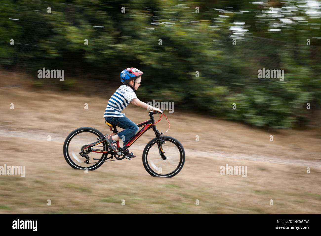 7 year old boy riding Merida Mountain bike down at gradient at speed Stock Photo