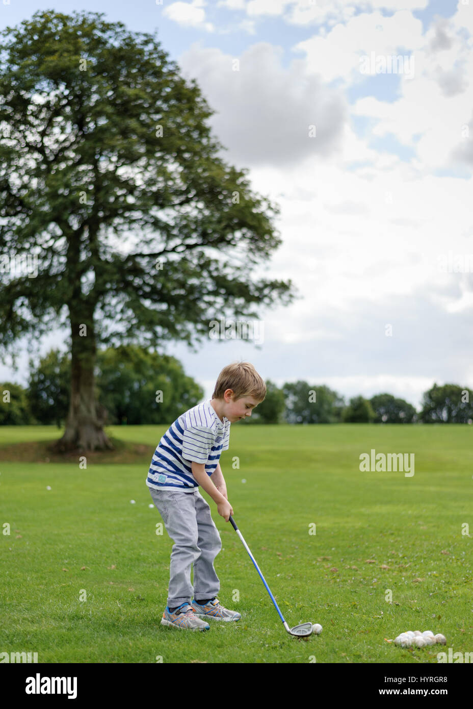 7 year old boy practising golf swing at Golf Club Stock Photo