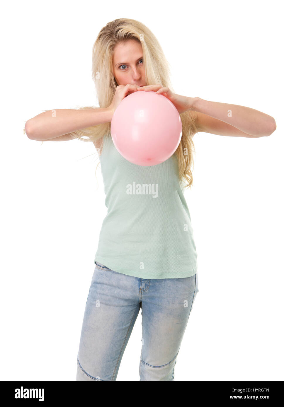 Close up portrait of a young blond woman inflating balloon on isolated white background Stock Photo