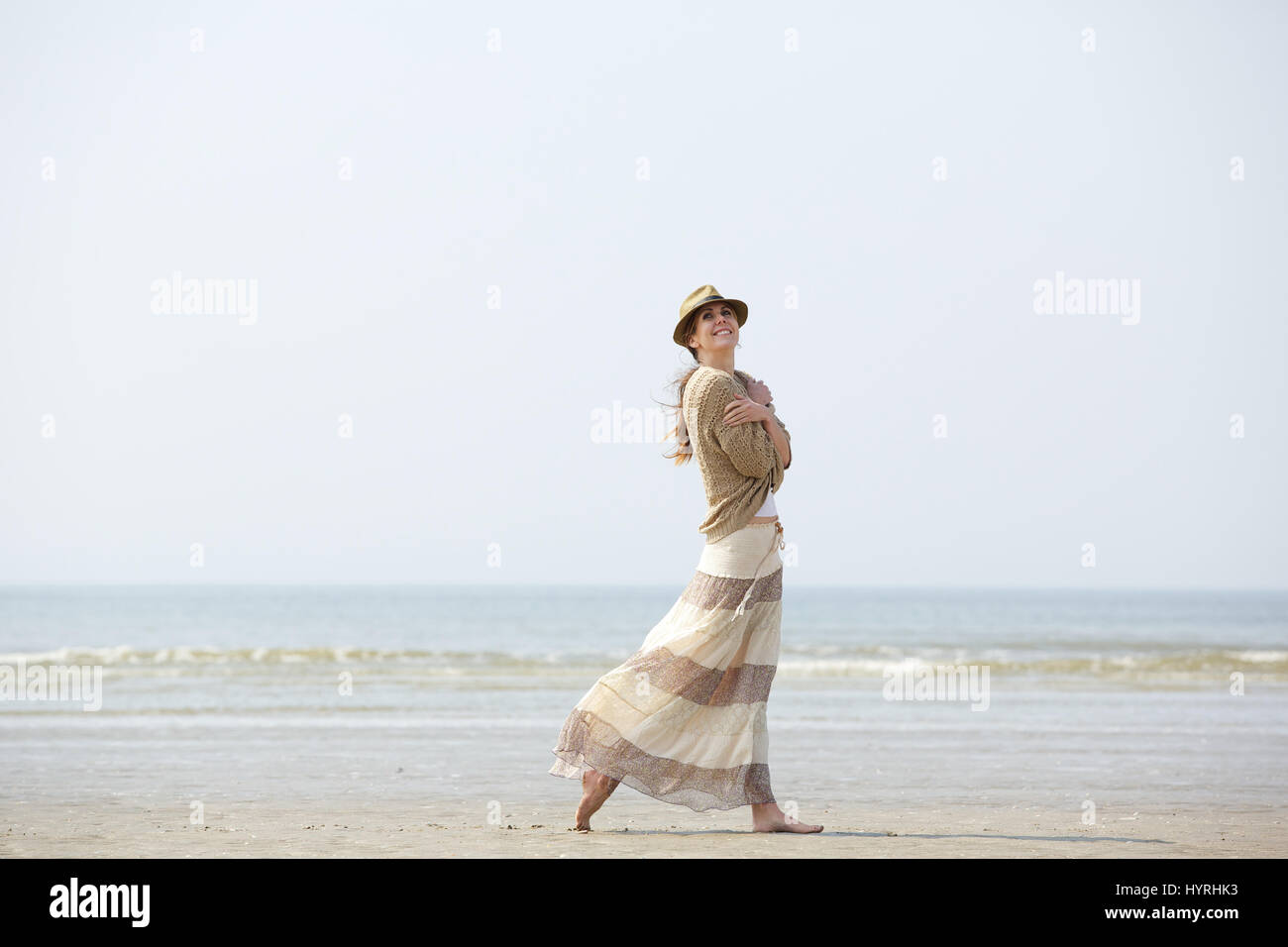 Portrait of a beautiful middle aged woman smiling and walking on the beach Stock Photo