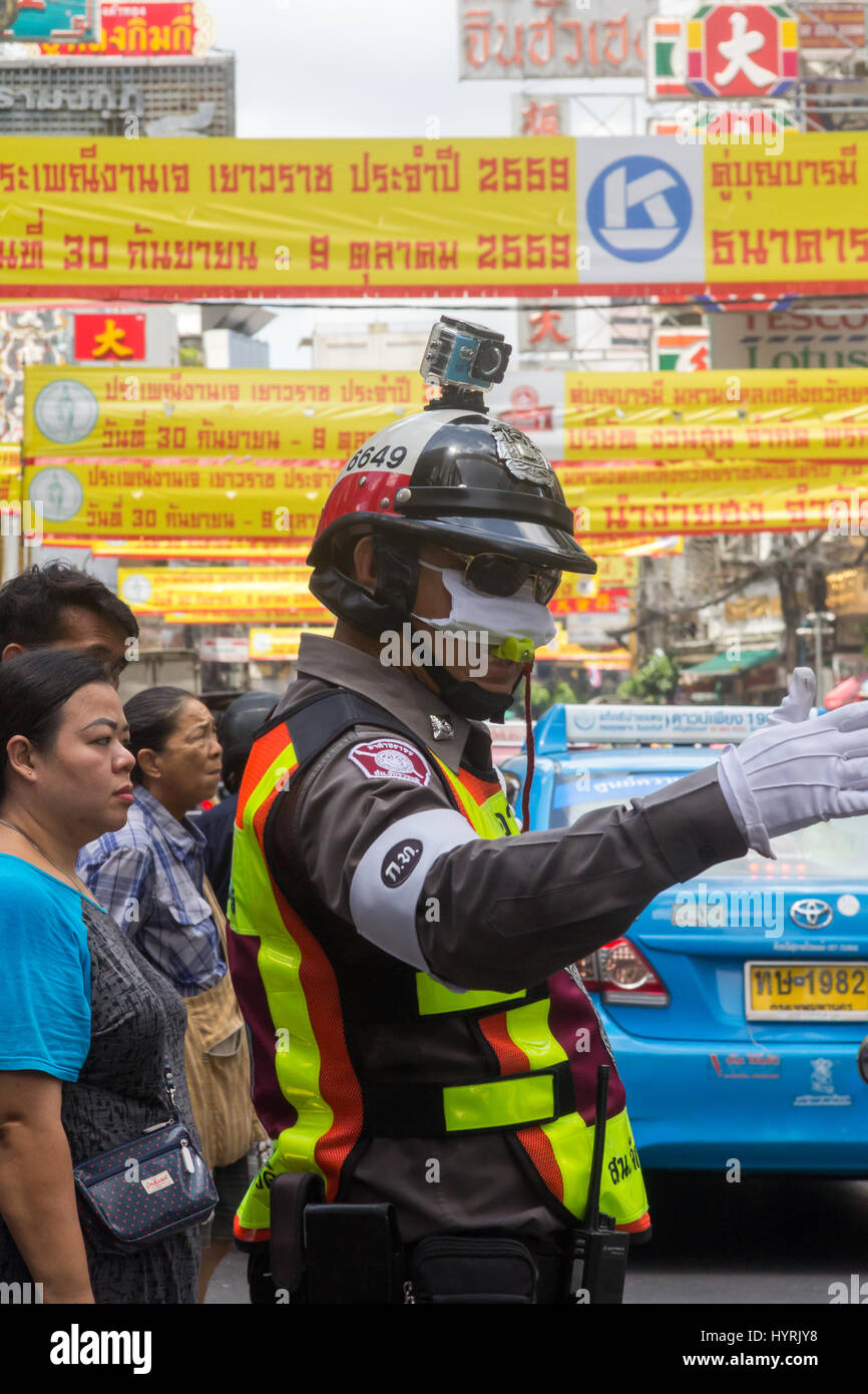 Policeman with go pro camera on his helmet directing traffic and pedestrians in CHinatown, Bangkok, Thailand Stock Photo