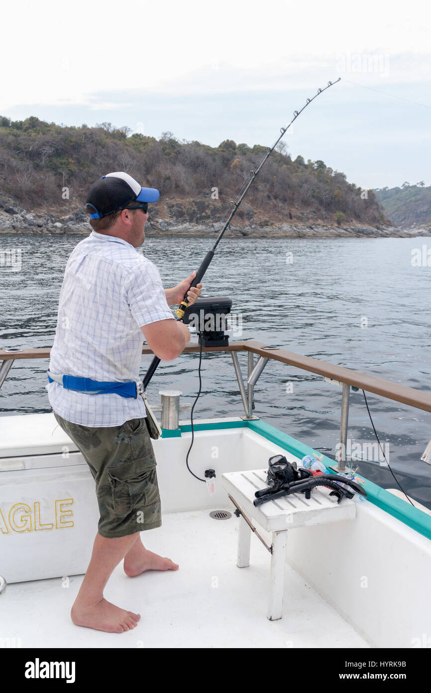 Man hooked into a fish on a boat in the Andaman sea off Phuket, Thailand Stock Photo