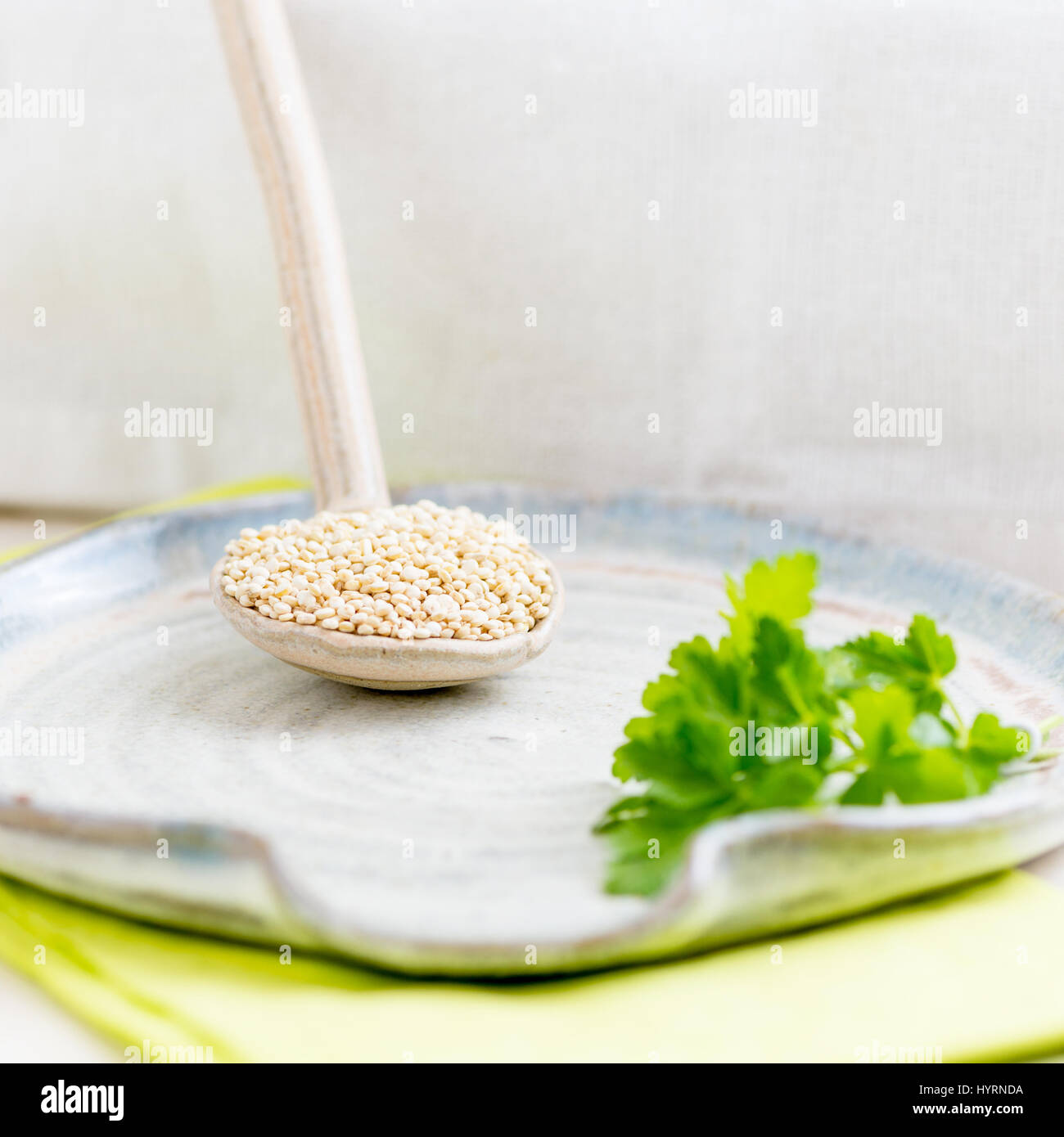 square image of gluten free bio quinoa in a ceramic spoon on a textured plate. room for copy space and text Stock Photo